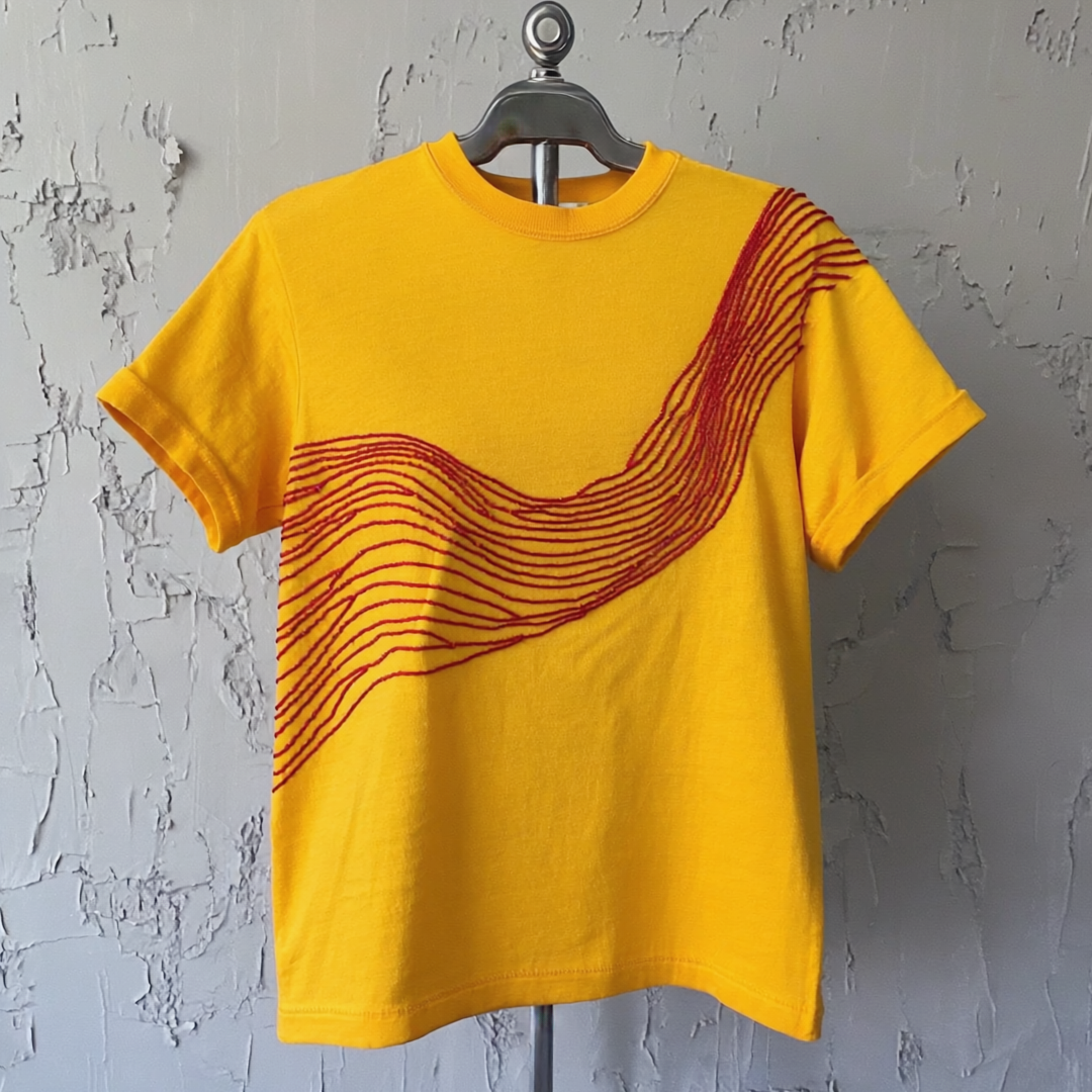 Yellow Bougie Tee with red chainstitch embroidery on hanger, showcasing artistic design.