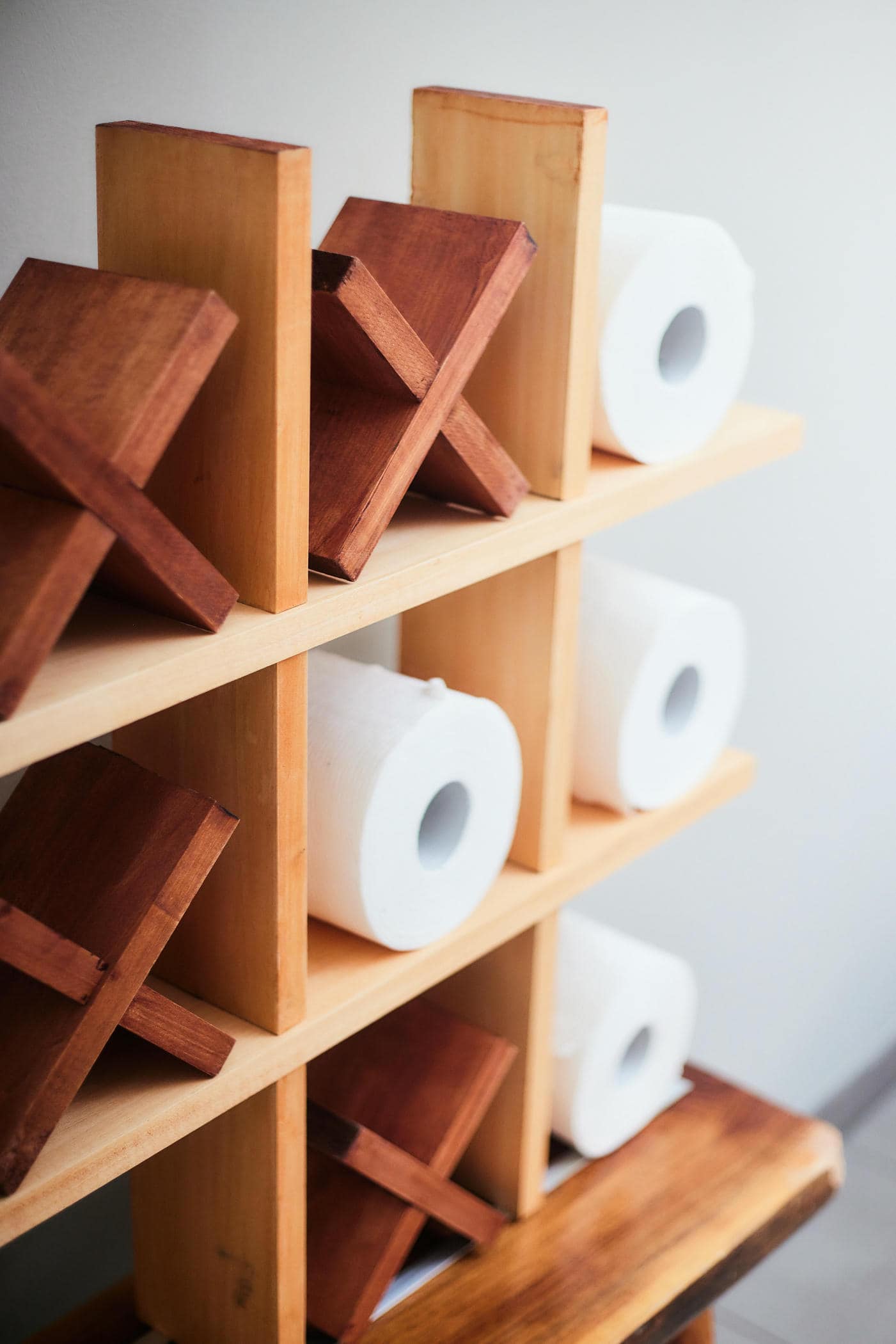 Wooden shelf with wooden blocks and toilet paper rolls against a white wall