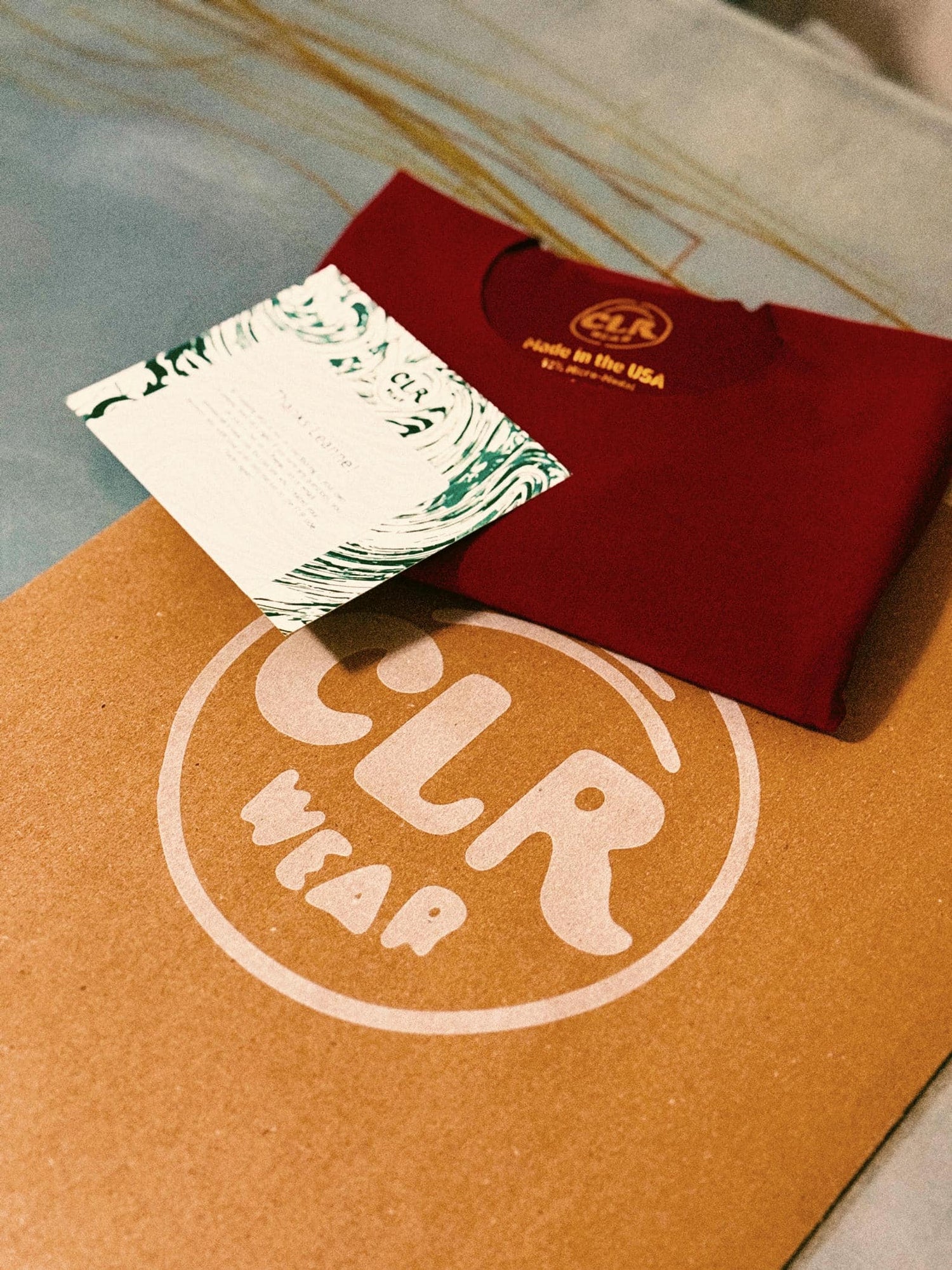 Red t-shirt with 'CLR Wear' logo on a brown surface