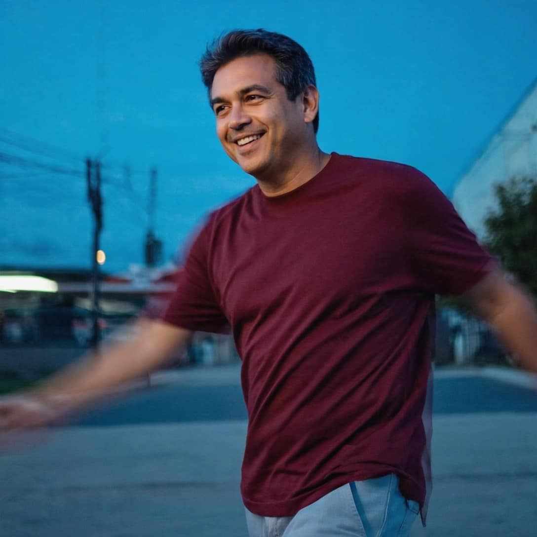 Man wearing The Basic Tee in maroon, evening outdoor setting.